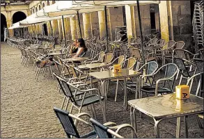  ?? AP/ALVARO BARRIENTOS ?? Two women sit outside an empty bar terrace at Plaza de la Constituci­on square in Vitoria, Spain, on Monday. The European Central Bank announced Thursday that it was looking to end its bondbuying program next month.