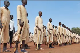  ?? (AP Photo/Maura Ajak) ?? Trainees parade with the wooden mock guns they use for practice during the visit of the defense minister to a military training center June 27 in Owiny Ki-Bul, Eastern Equatoria, South Sudan. At crowded camps in South Sudan, former enemies are meant to be joining forces and training as a unified security force after a five-year civil war so they can help the shattered country recover, but they can barely find enough food.