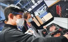  ?? CHEN YEHUA / XINHUA ?? An exhibitor ( left) presents beef products from South Africa at the Food and Agricultur­al Products exhibition area during the third China Internatio­nal Import Expo in Shanghai on Nov 7.