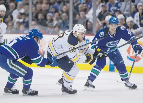  ?? PHOTOS: DARRYL DYCK/CANADIAN PRESS ?? Ryan O’Reilly of the Buffalo Sabres, centre, tries to manoeuvre around the checking of Vancouver Canucks Derek Dorsett, left, and Adam Cracknell during Monday’s NHL game in Vancouver. The Canucks and forward Radim Vrbata snapped out of their offensive...