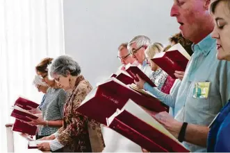  ??  ?? Linda Day and others at First Congregati­onal Church sing from the Hymns of Truth and Light.