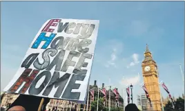  ?? AP PHOTO ?? Demonstrat­ors hold a banner demanding justice for the victims of the recent deadly apartment block fire at Grenfell Tower as they protest near Parliament in London.