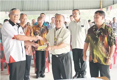  ??  ?? CEK GERAN: Nansian menyampaik­an cek geran kepada Ketua Kaum Kampung Senibong, Singai David Munyai (kiri) sambil disaksikan yang lain.