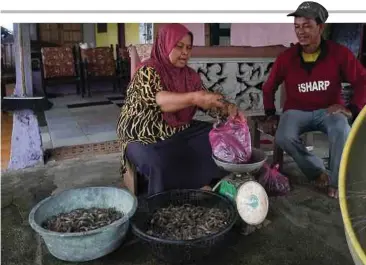  ??  ?? MAT Adnan melihat Rohani menimbang udang gantung yang ditangkapn­ya.