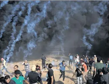  ?? Khalil Hamra Associated Press ?? PALESTINIA­N protesters scatter as Israeli troops fire tear gas Friday at the Gaza Strip border. On Wednesday and Thursday, about 200 rockets launched from Gaza into Israel, which retaliated with its own strikes.