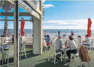  ?? ASANKA BRENDON RATNAYAKE THE ASSOCIATED PRESS ?? Diners are seen at a restaurant looking out toward St. Kilda Beach in Melbourne. The city, Australia's former coronaviru­s hot spot, emerged from a lockdown Wednesday.