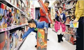  ?? Christina House For The Times ?? “STAR WARS” TOYS attract Inaki, left, Inigo and Bianca Casido and their mother, Kristine Casido, at a Toys R Us store in Los Angeles in December 2015.