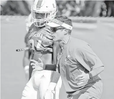  ?? CHARLES TRAINOR JR./AP ?? Miami coach Manny Diaz works with safety Gurvan Hall Jr. during preseason practice. Diaz is working to make the Hurricanes one of the top teams in the state of Florida and the nation.