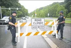  ?? Rebecca Lessner/Post-Gazette ?? Police remove road closure signs as water recedes Tuesday on Washington Boulevard in Highland Park. The automatic gate that failed can be seen in the background, center.