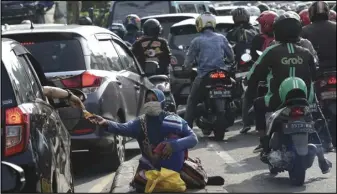  ?? ASSOCIATED PRESS ?? A motorist gives money to beggars while stuck in Monday morning rush hour traffic, in Jakarta, Indonesia.