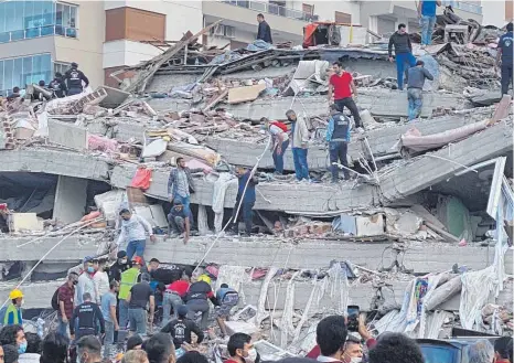  ?? FOTO: ISMAIL GOKMEN/DPA ?? Rettungskr­äfte und Anwohner versuchen in der westtürkis­chen Stadt Izmir Menschen zu befreien, die unter den Trümmern eines eingestürz­ten Gebäudes begraben sind.
