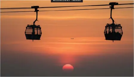  ?? Cartoonist Bethuel Mangena is on leave. | EPA ?? VISITORS ride a cable car at sunset in Hong Kong, China, this week. The cable car links Tung Chung, near the airport, to the village of Ngong Ping on Lantau Island.