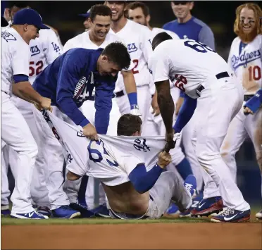  ?? KEVORK DJANSEZIAN — GETTY IMAGES ?? Kyle Farmer has his shirt ripped apart by Dodgers teammates after his double in the 11th drove in the tying and winning runs.