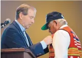  ?? RUSSELL CONTRERAS/ASSOCIATED PRESS ?? U.S. Sen. Tom Udall, D-N.M., pins replacemen­t medals on All Pueblo Council of Governors Chairman Edward Paul Torres during a ceremony at Isleta Pueblo on Friday.