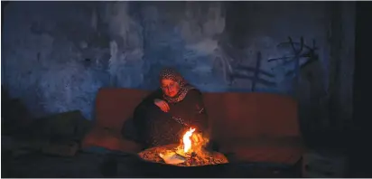  ?? (Mohammed Salem/Reuters) ?? A WOMAN WARMS herself by a fire inside her home in the northern Gaza Strip in January.