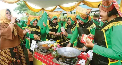  ?? BOY SLAMET/JAWA POS ?? AYOOO GOYANG: Tim perwakilan dari Kecamatan Krembung memasak mi dengan mengenakan baju adat Sumatera Barat kemarin.