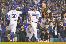  ?? MARCIO JOSE SANCHEZ/ASSOCIATED PRESS ?? The Dodgers’ Mookie Betts, left, is greeted by Walker Buehler, center, as Giants catcher Buster Posey waits after Betts hit a two-run home run that scored Buehler during Game 4 of an NL Division Series on Tuesday in Los Angeles.