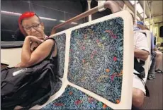  ??  ?? CINDY SOLORZANO of Van Nuys sits in a fabric seat on the way to downtown. Cloth seats are a rarity among major transit systems.