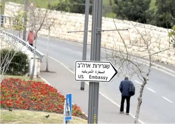  ??  ?? A man walks next to a road sign directing to the US embassy in Jerusalem. — Reuters photo