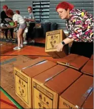  ??  ?? Parent Lisa Hoffman stacks cartons of packaged meals on a cart once she has finished sealing them.