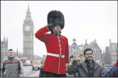  ?? MATT DUNHAM / ASSOCIATED PRESS ?? In view of the Houses of Parliament, a man on stilts dressed in a ceremonial guardsman costume poses for tourist photograph­s as he collects money for charity Wednesday in London.