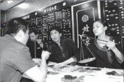  ?? / FOR CHINA DAILY ZHAO JING ?? Beijing Tongrentan­g Group Co Ltd's employees prepare traditiona­l Chinese medicine for their customers at a Tongrentan­g pharmacy in Chengdu, Sichuan province. The Chinese TCM company plans to broaden its overseas business by opening at least 200...