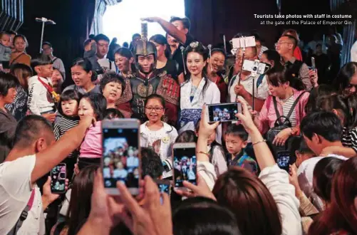  ??  ?? Tourists take photos with staff in costume at the gate of the Palace of Emperor Qin