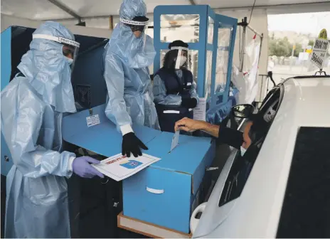  ?? Reuters ?? Election officials in protective gear instruct a man as he votes from a car at a special polling station for vulnerable citizens