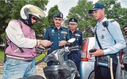  ??  ?? AZMAN (dua dari kiri) memeriksa lesen penunggang motosikal ketika Op Selamat di Selangor di Taman Bukit Saga Seksyen 26, Shah Alam, semalam.