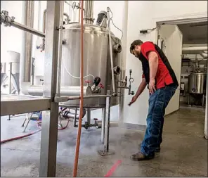  ?? NWA Media/ANTHONY REYES ?? Jesse Core, owner of Core Brewing and Distilling Co. in Springdale, adjusts the steam on his still. Core recently obtained state and federal permits and plans to produce single malt whiskey, moonshine and brandy.