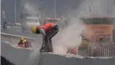  ?? — AFP ?? Dust billows as a worker grinds the concrete divider of an under- constructi­on flyover as vehicle drive through smog covered New Delhi on Monday.