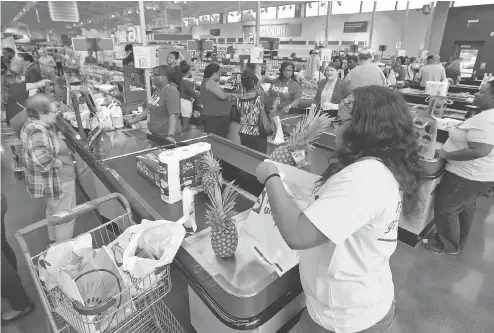  ?? STEVE HELBER / THE ASSOCIATED PRESS ?? Shoppers get their groceries bagged during the grand opening of a Lidl grocery store in Virginia Beach, Va., last week. Several Lidl stores opened across the U.S. last week as the German chain tries to win over American consumers with curated wines,...