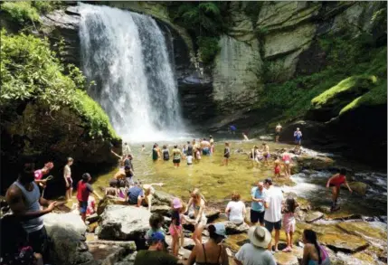  ?? HILLARY SPEED VIA AP ?? This photo shows swimmers wading in at the base of Looking Glass Falls, located in the Pisgah National Forest, between Brevard, N.C., and the Blue Ridge Parkway. Known as “The Land of the Waterfalls,” Transylvan­ia County boasts more than 250 waterfalls that attract visitors every year.