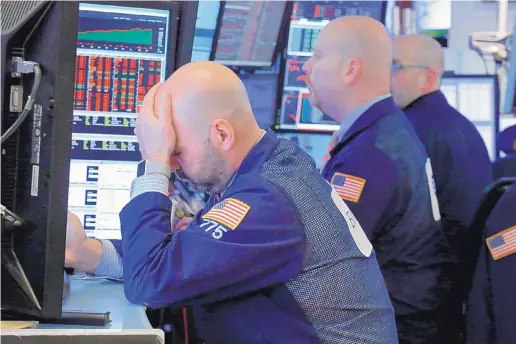  ?? RICHARD DREW/ASSOCIATED PRESS ?? Fred DeMarco, left, works with colleagues at the New York Stock Exchange on Thursday. Stocks fell sharply after the president announced China tariffs.