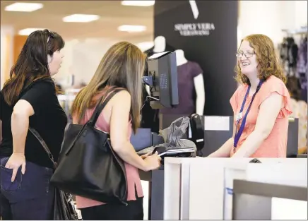  ?? Chuck Burton / Associated Press file ?? Cashier Liz Moore, right, checks out customers Christie Meeks, center, and Lisa Starnes, left, at a Kohl’s store in Concord, N.C.