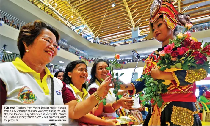  ?? CHRISTIAN MARK LIM ?? FOR YOU. Teachers from Matina District receive flowers from a lady wearing a costume yesterday during the 2016 National Teachers' Day celebratio­n at Martin Hall, Ateneo de Davao University where some 4,500 teachers joined the program.