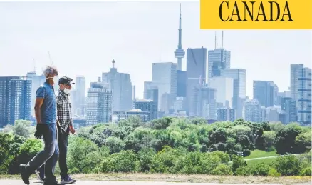  ?? PETER J THOMPSON / FOR NATIONAL POST ?? Pedestrian­s in masks walk along Toronto’s Broadview Avenue on Tuesday. The Toronto area has been hit much harder than elsewhere in Ontario.