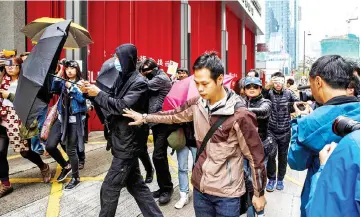  ?? — AFP photo ?? Supporters use umbrellas to cover their faces while surrounded by members of the media, as they leave the District Court in Hong Kong, after three young protesters were jailed for three years on ‘riot’ charges for their part in the ‘fishball riots’.