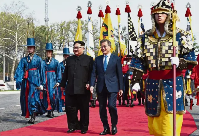  ?? — AP ?? A tale of two Koreas: Kim (left) and Moon walking together at the border village of Panmunjom. Kim made history by crossing over the world’s most heavily armed border to greet Moon for the landmark talks on nuclear weapons.