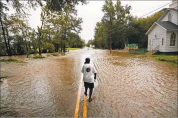  ?? David Goldman Associated Press ?? A WOMAN WALKS through flooding Sunday in Fayettevil­le, N.C. “Whatever God got for me, he’s going to give to me,” she says. “He said he’s going to take care of us, and that’s what I’m going to have to live on.”