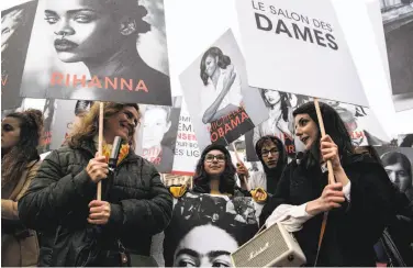  ?? Christophe Archambaul­t / AFP / Getty Images ?? Demonstrat­ors in Paris hold pictures of famous women — including Michelle Obama — to mark the day.