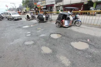  ??  ?? Apalit Mayor Peter Nucom shows photos of huge pot holes along MacArthur Highway in Barangay San Vicente which is fast deteriorat­ing due to heavy rains and volume of vehicles.---