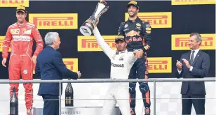  ?? AP ?? Mercedes driver Lewis Hamilton of Britain (centre) is jubilant while raising his trophy on the podium after winning the Belgian Formula One Grand Prix in Spa-Francorcha­mps yesterday. Ferrari driver Sebastian Vettel of Germany (left) placed second and...