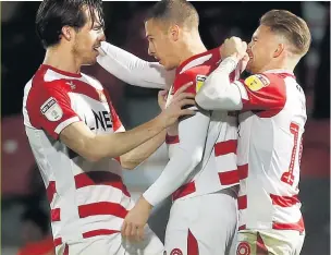  ??  ?? HANDS ON Tommy Rowe in the centre of attention after his vital late strike for Doncaster