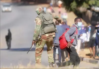  ??  ?? A member of the Zimbabwe National Army whips one of the people blocked from getting into Harare central business district yesterday as authoritie­s tightened the coronaviru­s lockdown after infections spiked to 206 on Monday