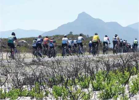  ?? PICTURE: IAN LANDSBERG ?? LIFE CYCLE: Cyclists taking part in this year’s Cape Town Cycle Tour make their way through the scorched earth near Ocean View where a fire broke out in January.