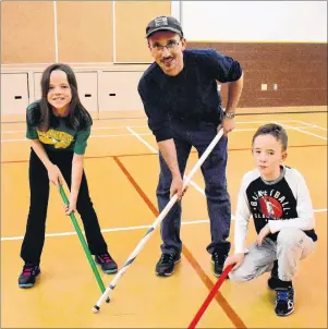  ?? DAVID JALA/CAPE BRETON POST ?? Eleven-year-old twins Rebecca, left, and Reilly flank father Trevor MacKinnon while posing for pictures at the weekly Sunday evening Multisport session at Harboursid­e Elementary School in Whitney Pier. Reilly, who has autism, enjoys the support of his...