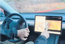  ?? GILLIAN FLACCUS/AP ?? Vince Patton plays video games displayed on the center screen of his Tesla automobile while driving this month on a closed course in Portland, Oregon.