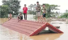  ?? AP ?? People take refuge on a rooftop in the Attapeu province of southeaste­rn Laos on Tuesday after the collapse of a dam.