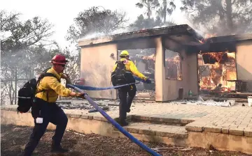  ??  ?? Firefighte­rs knock down flames in the Point Dume neighbourh­ood of Malibu, California, after the Woolsey Fire tore through the area overnight. . — AFP photo